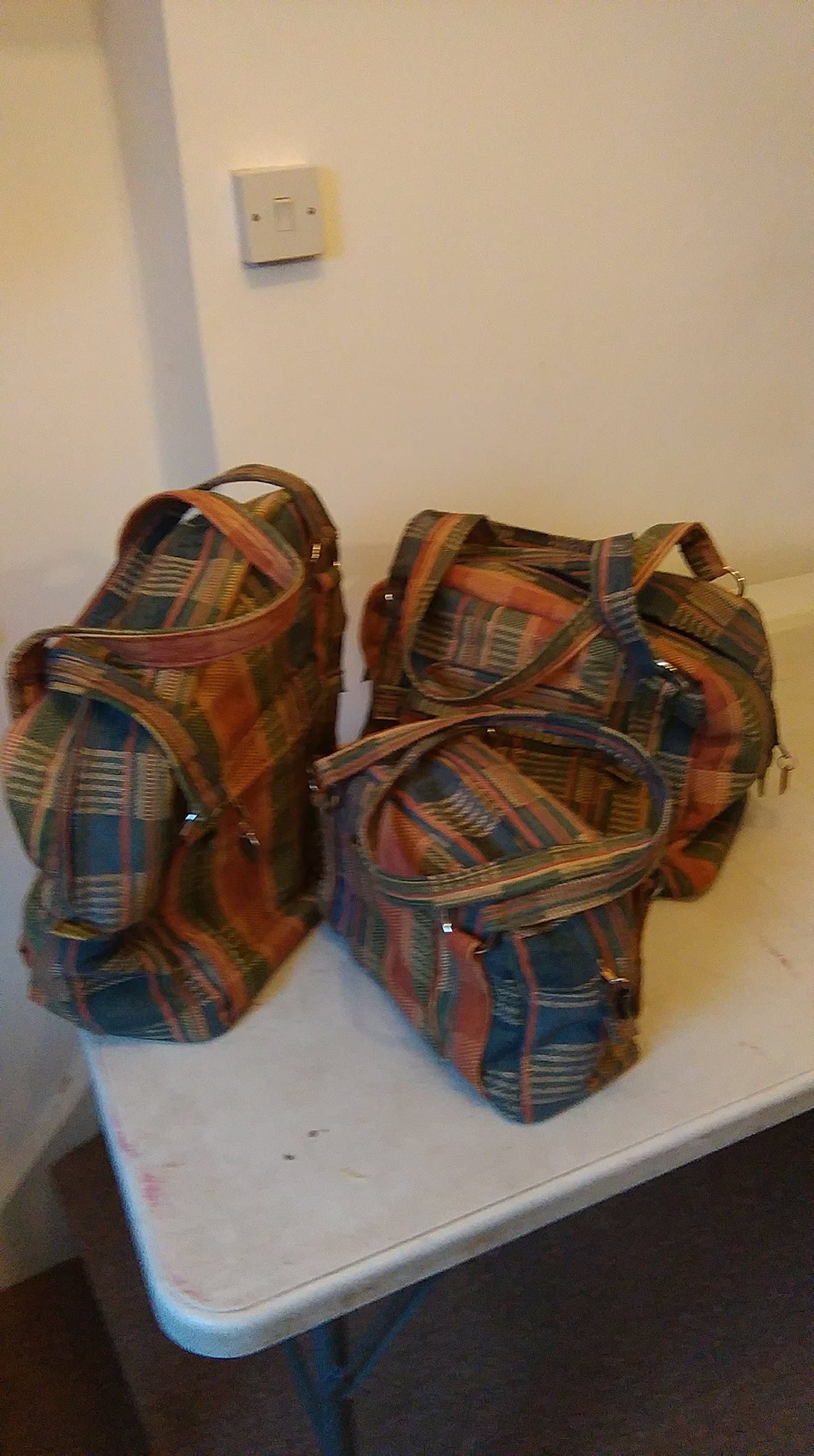 Set of three plaid fabric carpet bags.